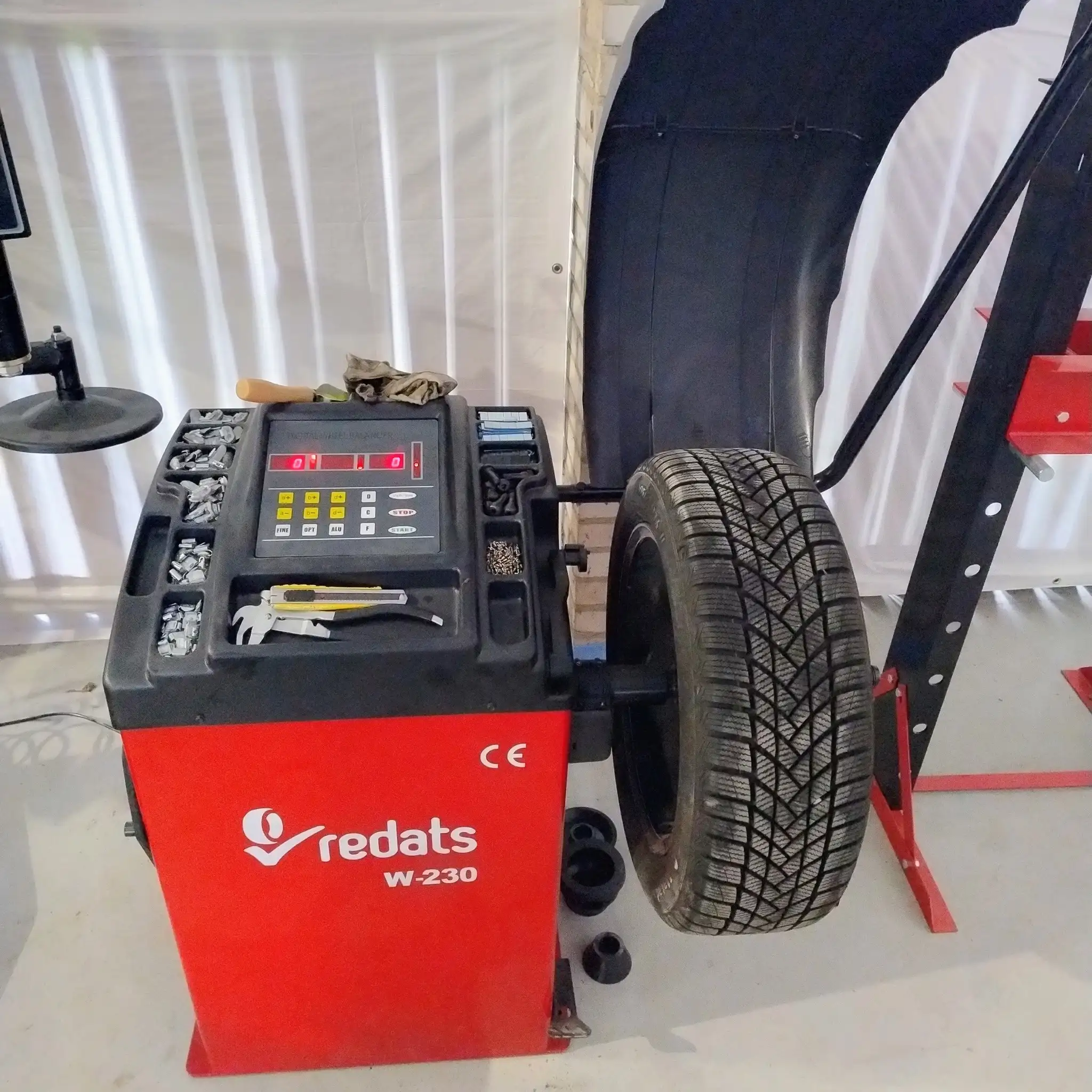 Maszyna do wyważania kół z założoną oponą w warsztacie samochodowym.